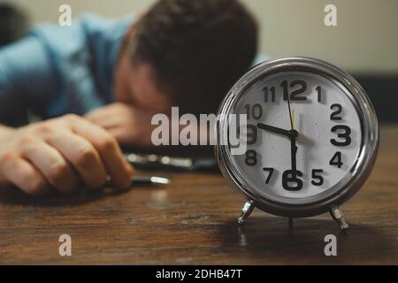 The clock shows half past nine in the evening. Man fell asleep at work. Stock Photo