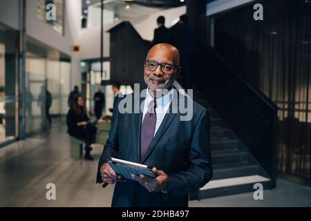 Portrait of entrepreneur in formal wear while standing with digital tablet in office Stock Photo