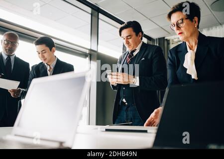 Business people working while standing in board room at office Stock Photo