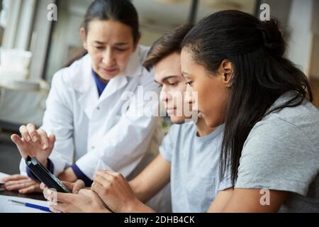 Young students using calculator by mature teacher in engineering classroom Stock Photo