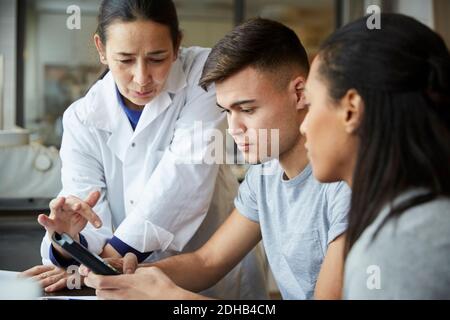 Mature teacher with young students using calculator in engineering classroom Stock Photo