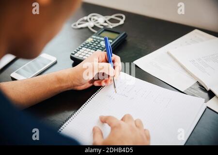 Cropped image young male university student writing in book at classroom Stock Photo