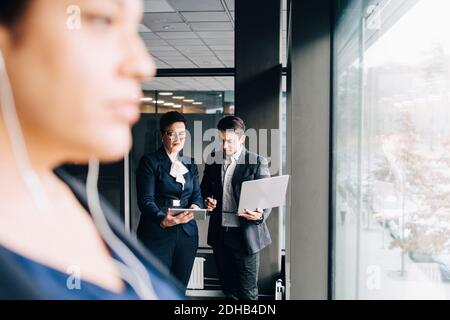 Senior businesswoman showing digital tablet to colleague in conference room at office Stock Photo