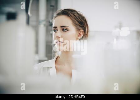 Confident young female student looking away while standing in laboratory Stock Photo