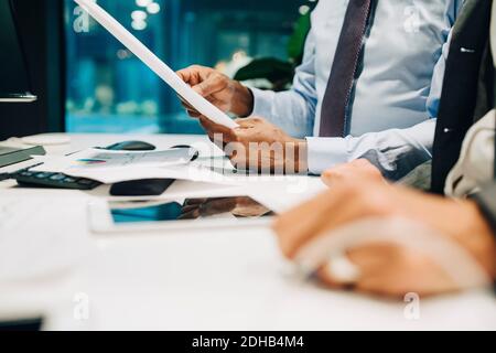Midsection of businessman holding document in meeting at office desk Stock Photo