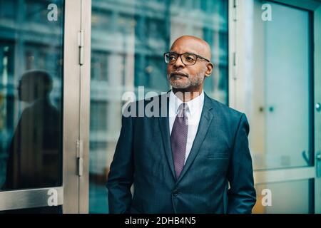 Confident thoughtful businessman wearing suit looking away at office Stock Photo