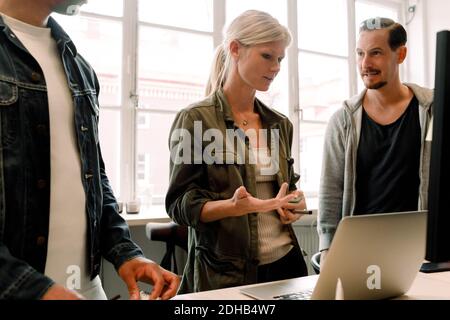 Business colleagues discussing project over laptop at office desk Stock Photo