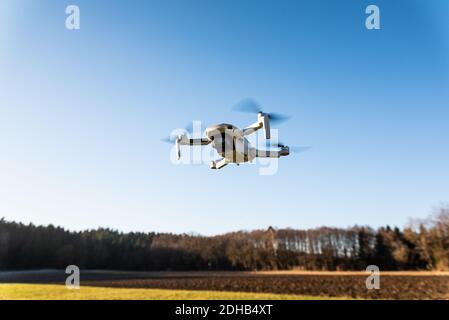 Close up shoot of a DJI Quadcopter Drone Mavic mini 249g. Drone flying against sun background. Stock Photo