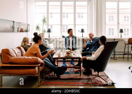 Creative male and female business colleagues talking during break in office Stock Photo