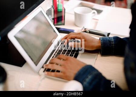 Cropped hand of male business executive working on laptop at desk Stock Photo