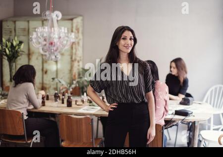 Portrait of smiling young woman standing with hand on hip at workshop Stock Photo