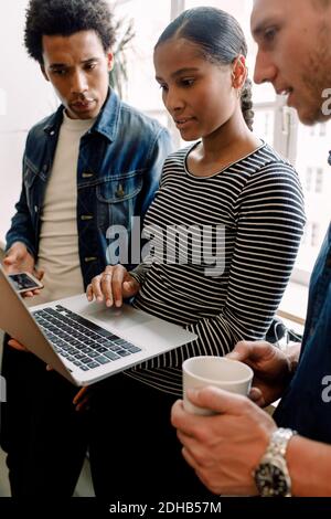Young female entrepreneur holding laptop while discussing with executives in office Stock Photo
