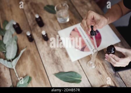 High angle view of woman using pipette for mixing liquid in test tube at perfume workshop Stock Photo