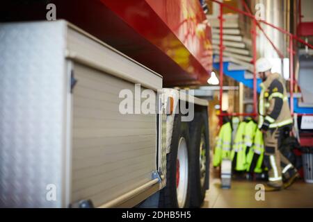 Cropped image of fire engine with worker in background at fire station Stock Photo
