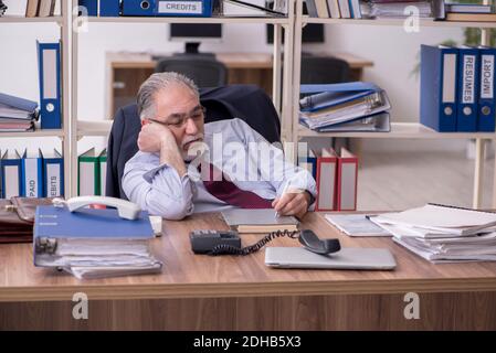 Old male employee unhappy with excessive work Stock Photo