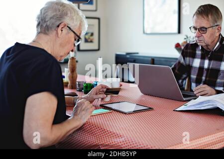 Senior couple using technologies while sitting at dining table Stock Photo