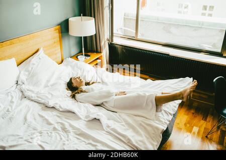 Smiling woman in bathrobe having fun on bed at hotel room Stock Photo