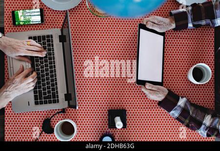 Directly above view of retired couple using technologies at dining table Stock Photo