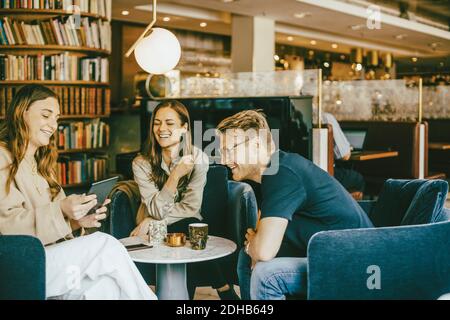Happy woman showing digital tablet to friends while sitting at hotel Stock Photo
