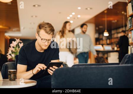 Mid adult man using digital tablet while sitting in restaurant during weekend Stock Photo