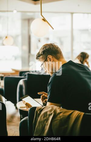 Side view of man using digital tablet while sitting in restaurant Stock Photo