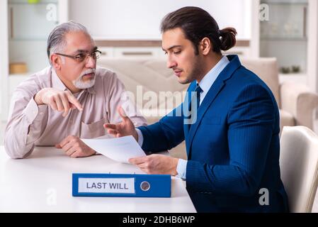 Young male lawyer visiting old man in testament concept Stock Photo