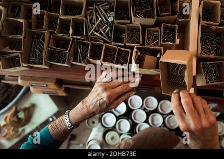 Hands of senior female sales clerk removing nails from cardboard box in hardware store Stock Photo
