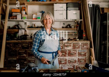 Portrait of confident senior female entrepreneur holding set square at workshop Stock Photo