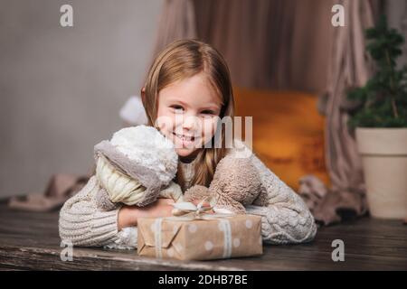 Cutre little girl lying among Christmas gifts at home . Stock Photo