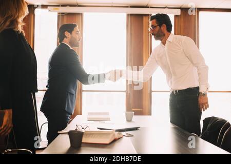 Businessman shaking hands with male lawyer after meeting in board room Stock Photo