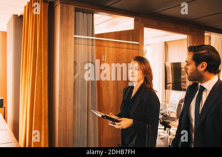 Male and female lawyers discussing while walking in office corridor Stock Photo