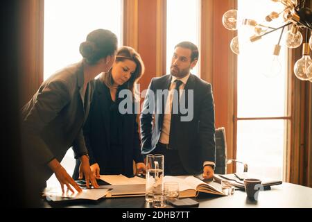 Male and female legal professionals discussing over documents at office meeting Stock Photo