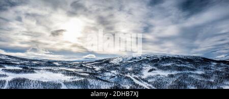 Scenic aerial panorama view on Scandinavian Mountains close to Joesjo lake in Swedish Lapland in winter cover, Sun behind clouds, frosty sunny day. Mu Stock Photo