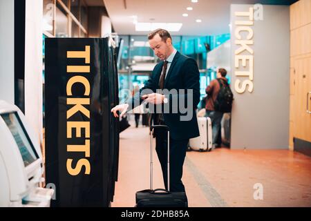 Mature businessman buying tickets in airport Stock Photo