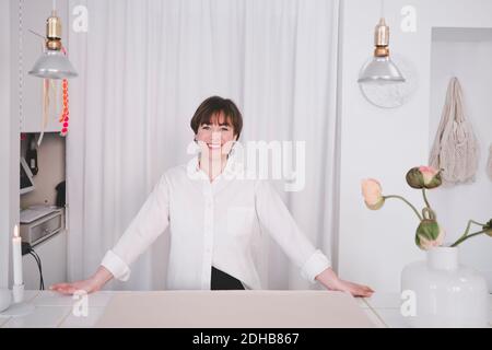 Portrait of smiling female interior designer standing at desk in studio Stock Photo
