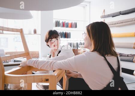 Female upholstery workers are working on chair in workshop Stock Photo