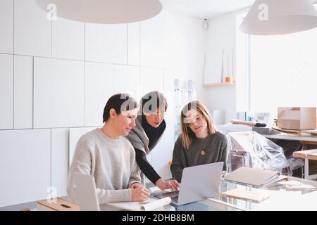 Female fashion designers discussing over laptop at desk in workshop Stock Photo