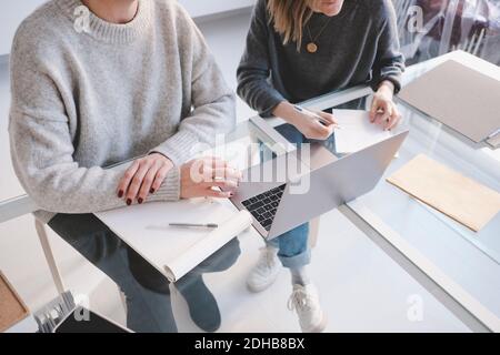High angle view of female interior designers discussing over laptop at desk in workshop Stock Photo
