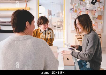 Smiling interior designer discussing with colleagues at desk in workshop Stock Photo