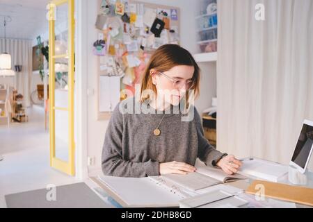 Female upholstery worker with documents sitting at desk in store Stock Photo