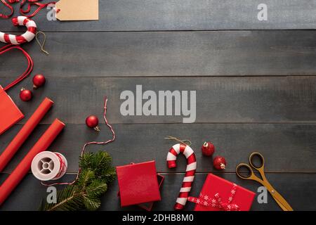 Christmas presents preparation. Gift boxes wrapping flat lay on blue wooden background, top view.  Red color ornaments and accessories, card template, Stock Photo