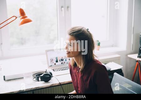 Confident businesswoman looking away while sitting at desk in office Stock Photo