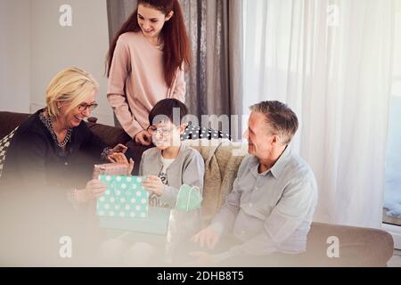 Smiling boy receiving birthday gifts from family at home Stock Photo