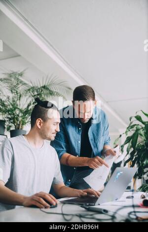 Creative businessmen discussing over document at desk in office Stock Photo
