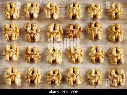 Walnuts halves on wooden chopping board, top view. Stock Photo
