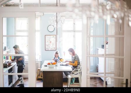 Woman using laptop while sitting with girl studying at kitchen island Stock Photo