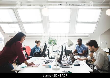 Male and female professionals using computers on desk in creative office Stock Photo