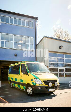 Yellow ambulance parked outside hospital against sky Stock Photo