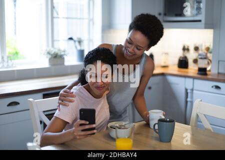 Mixed race female couple taking a selfie during breakfast in kichen. self isolation quality time at home together during coronavirus covid 19 pandemic Stock Photo
