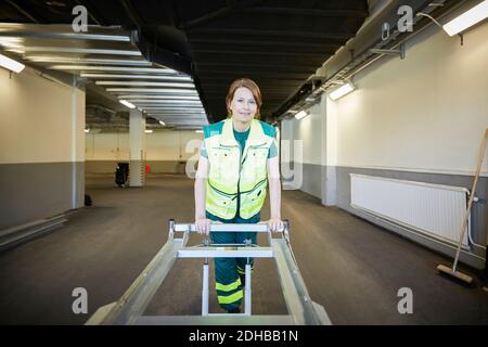 Portrait of female paramedic with stretcher in corridor at hospital Stock Photo